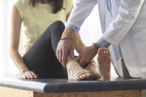Doctor wrapping a female patient's ankle