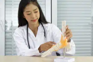 foot and ankle surgeon pointing at human skeleton foot ankle bone joint anatomy model,