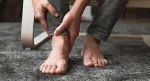 Foot pain, man suffering from feet ache at home due to flat feet
