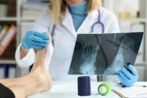 A female foot and ankle specialist is examining a patient with a leg injury during an appointment.