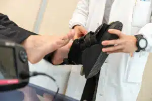 A foot doctor fitting an orthopedic shoe during a consultation for a patient seeking treatment for bunions.