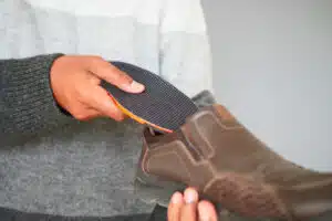 Image of a man inserting personalized orthopedic insoles into his shoes.