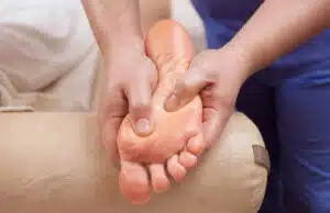 A podiatrist examines and massages the patient's foot for heel pain relief.