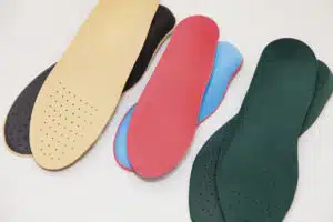 Different colored personalized shoe inserts can serve as orthopedic insoles for footwear against a white background.