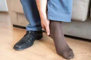 Man touching his foot due to heel pain caused by plantar fasciitis.