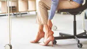Businesswoman with heel pain in office.