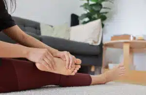 Woman massaging her painful foot and toes with red highlight on sole.