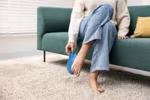 Senior woman with flat feet problem is fitting orthopedic insole at home